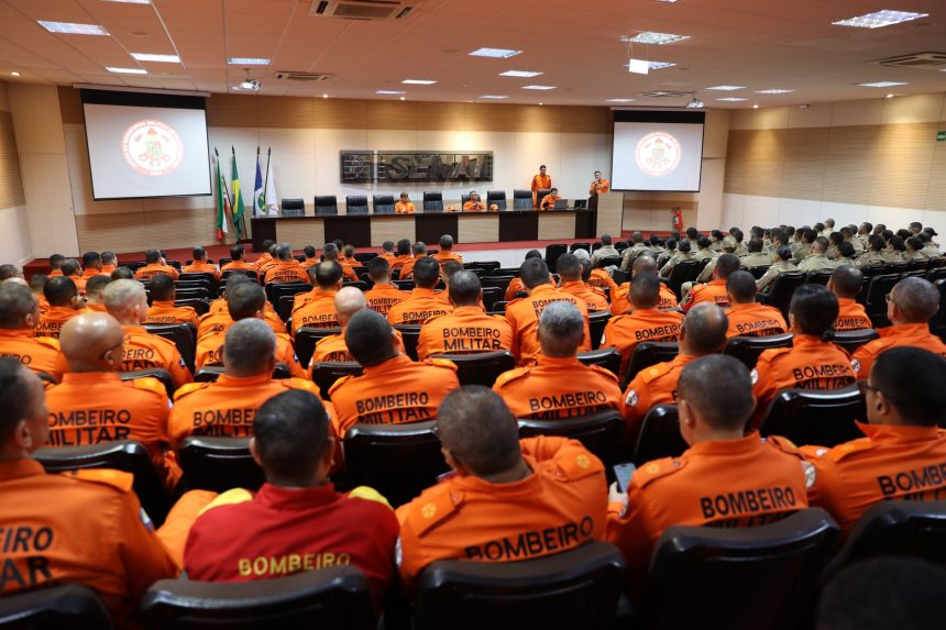 Bombeiros militares de uniforme laranja participam de uma atividade de treinamento estratégico ao ar livre.