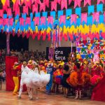 Dançarinos se apresentam em uma celebração cultural brasileira decorada com elementos coloridos.