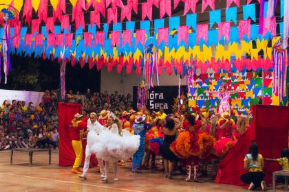 Dançarinos se apresentam em uma celebração cultural brasileira decorada com elementos coloridos.