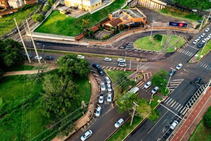 Vista aérea de um cruzamento urbano movimentado, com veículos circulando por diferentes vias.