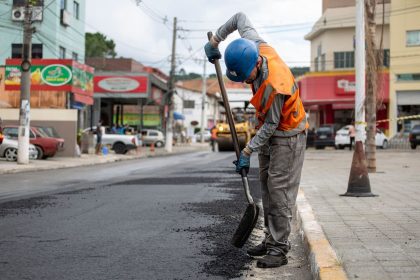 Trabalhador pavimenta uma rua com uma pá durante uma obra viária.