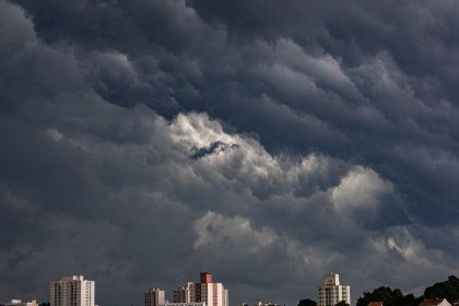Nuvens escuras e carregadas se aproximam de edifícios em uma área urbana.