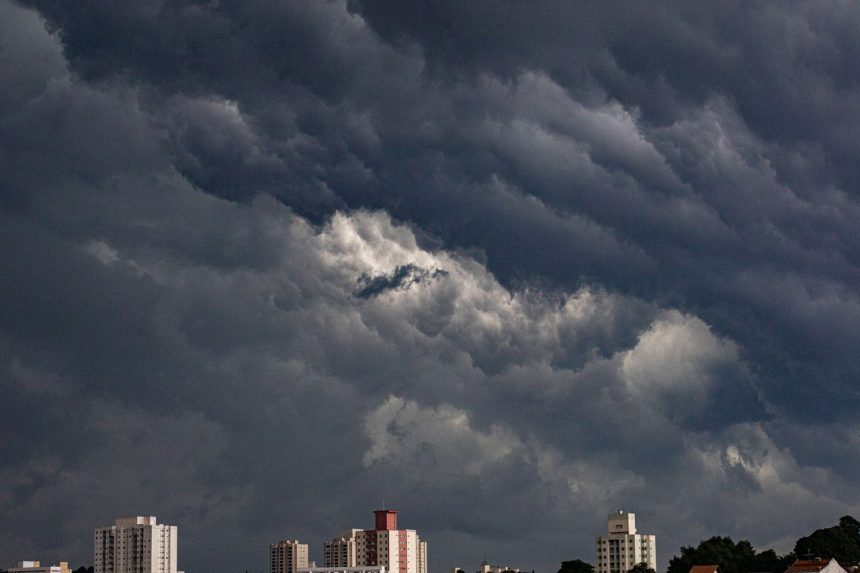 Nuvens escuras e carregadas se aproximam de edifícios em uma área urbana.