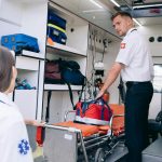 Dois paramédicos organizam materiais médicos dentro de uma ambulância para atendimentos de emergência.