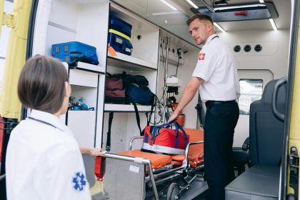 Dois paramédicos organizam materiais médicos dentro de uma ambulância para atendimentos de emergência.